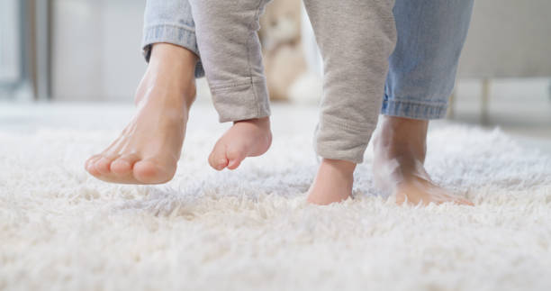 a woman and baby walking on carpet